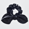 Mini silk bow scrunchie in black with white accents on alight grey background