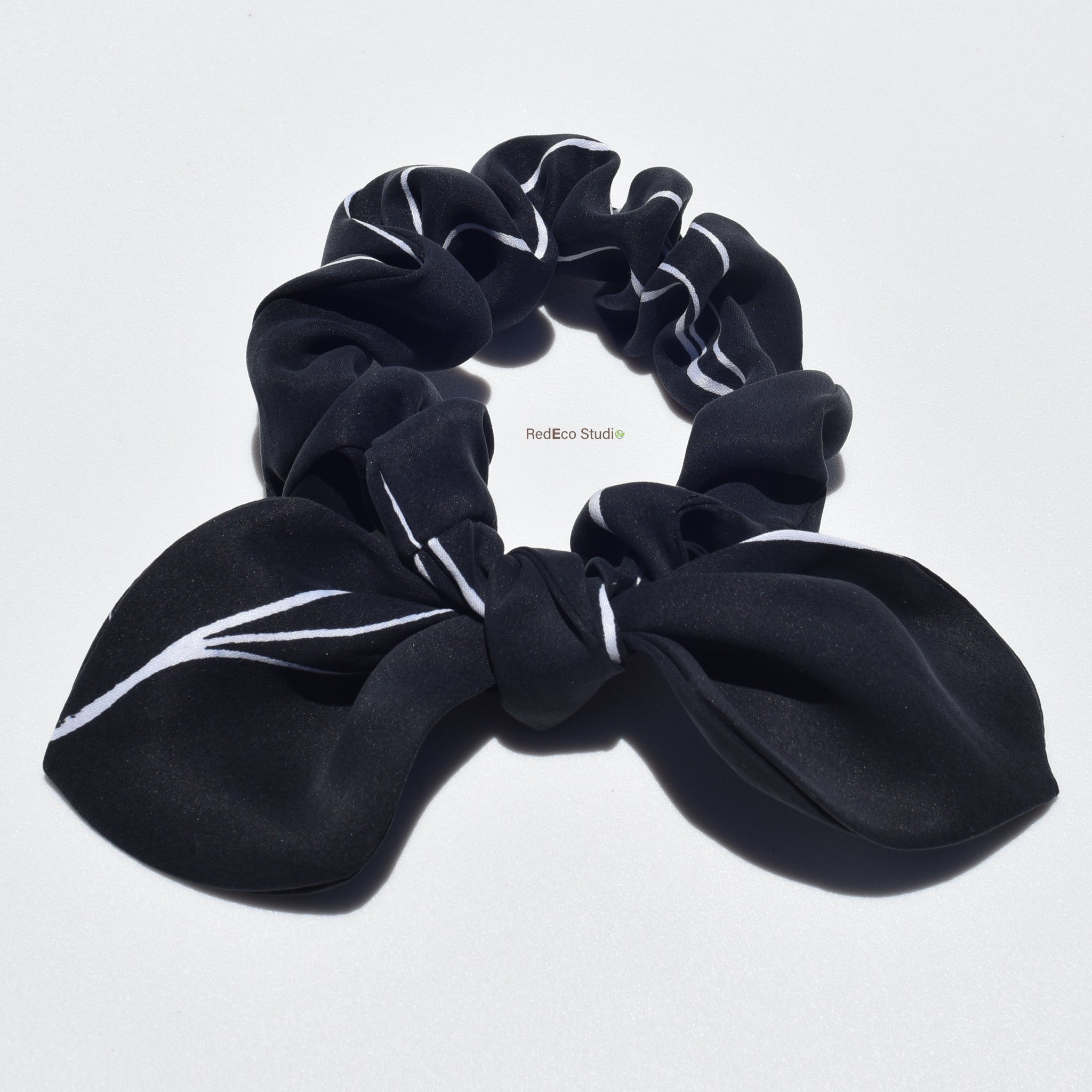 Mini silk bow scrunchie in black with white accents on alight grey background